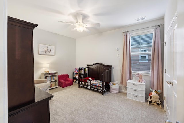 bedroom with ceiling fan, light carpet, and a nursery area