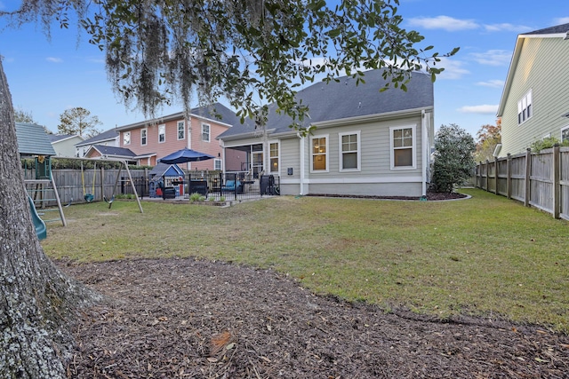 back of property with a playground and a yard