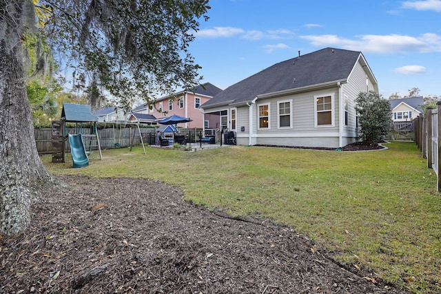 rear view of property with a yard and a playground