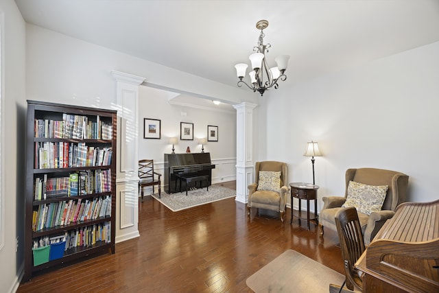 sitting room with dark hardwood / wood-style floors, an inviting chandelier, and decorative columns