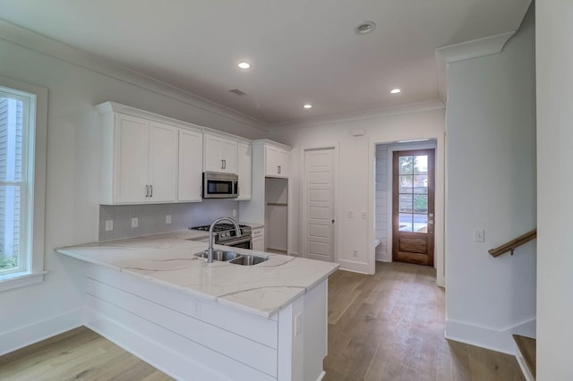 kitchen featuring white cabinets, appliances with stainless steel finishes, a healthy amount of sunlight, and light hardwood / wood-style flooring