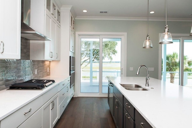 kitchen with pendant lighting, wall chimney range hood, sink, dark hardwood / wood-style floors, and white cabinets