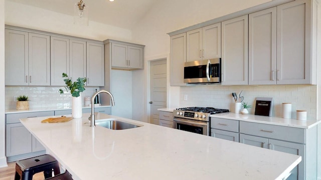 kitchen featuring appliances with stainless steel finishes, sink, backsplash, and a kitchen bar