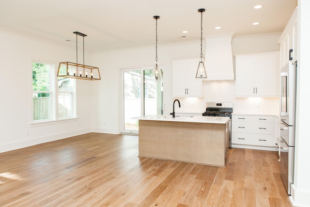 kitchen with hanging light fixtures, light hardwood / wood-style floors, white cabinets, a wealth of natural light, and tasteful backsplash