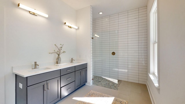 bathroom with tiled shower, dual vanity, and tile flooring