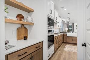 kitchen with pendant lighting, brown cabinets, open shelves, light countertops, and oven