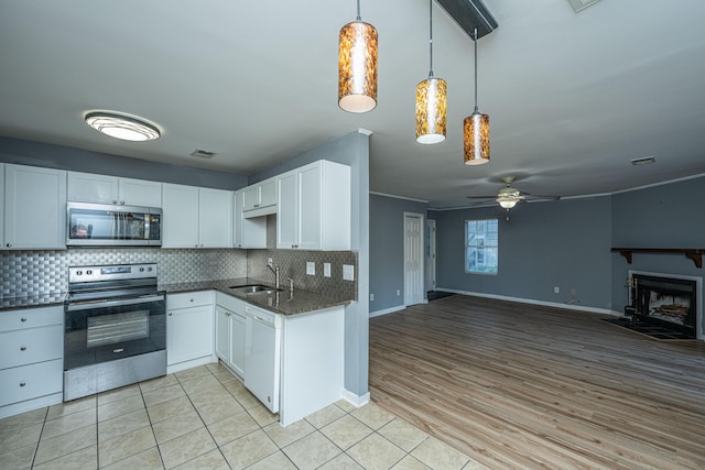 kitchen featuring white cabinets, light hardwood / wood-style floors, stainless steel appliances, and pendant lighting