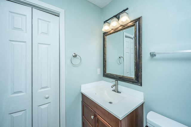 bathroom featuring vanity, a textured ceiling, and toilet