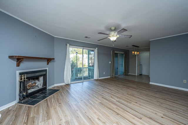 unfurnished living room with a tiled fireplace, hardwood / wood-style floors, ceiling fan with notable chandelier, and ornamental molding