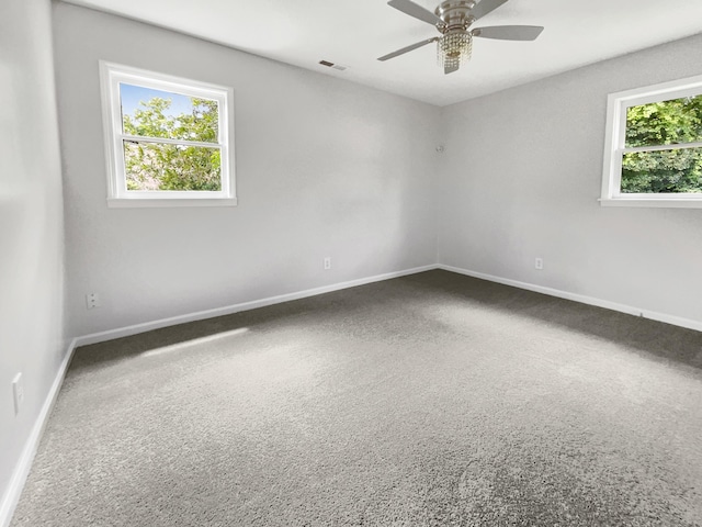 empty room featuring a wealth of natural light, visible vents, baseboards, and ceiling fan