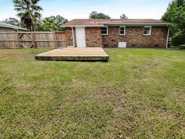 rear view of property with brick siding, fence, a wooden deck, a yard, and crawl space