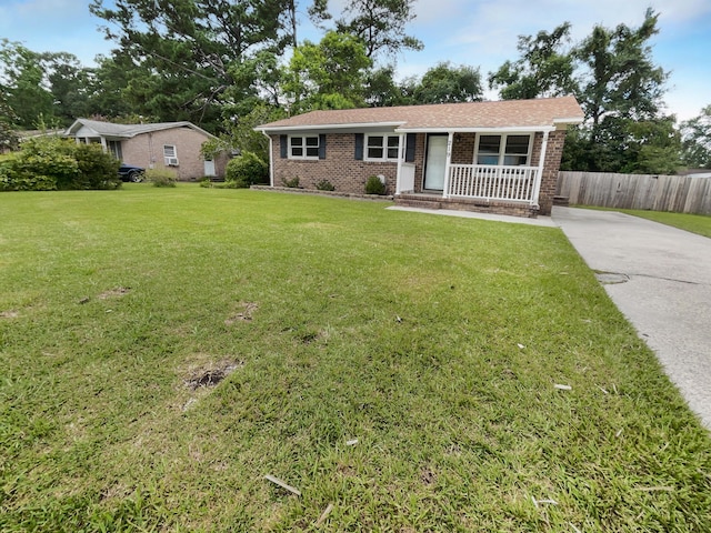 ranch-style house featuring brick siding, a porch, a front yard, and fence