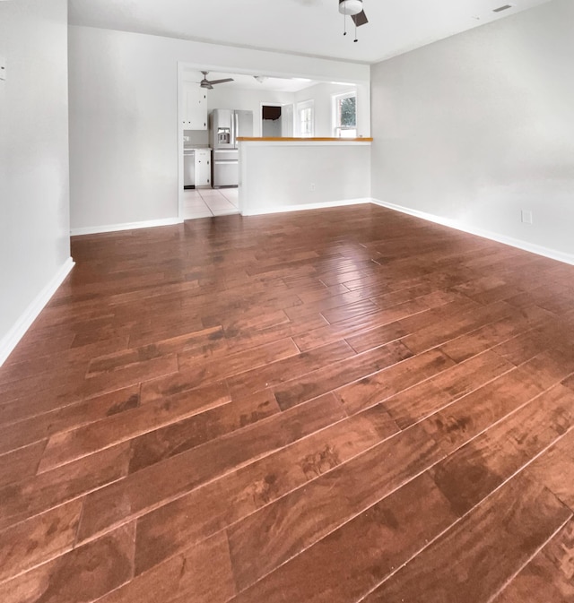 unfurnished living room featuring baseboards, wood-type flooring, and ceiling fan