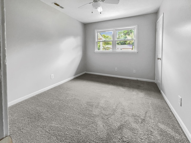 carpeted spare room with visible vents, baseboards, and a ceiling fan