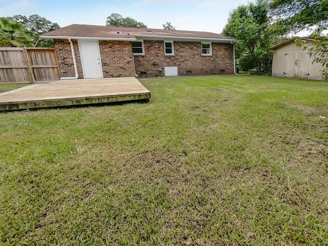 back of property with a deck, fence, a yard, crawl space, and brick siding