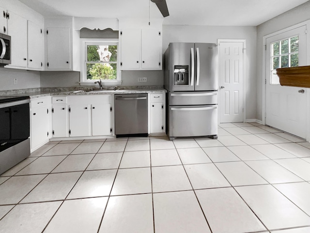 kitchen featuring light tile patterned floors, white cabinets, stainless steel appliances, and a healthy amount of sunlight