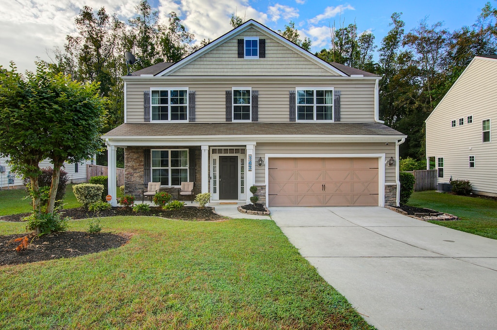 view of front of home with a garage, a front lawn, and covered porch