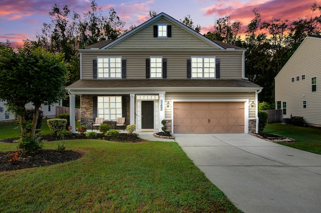 view of front of home with a yard, a porch, and a garage