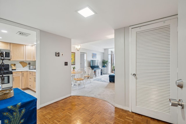 interior space featuring visible vents, appliances with stainless steel finishes, open floor plan, light countertops, and light brown cabinets