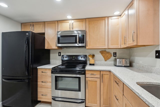 kitchen with appliances with stainless steel finishes, recessed lighting, light brown cabinets, and light stone countertops