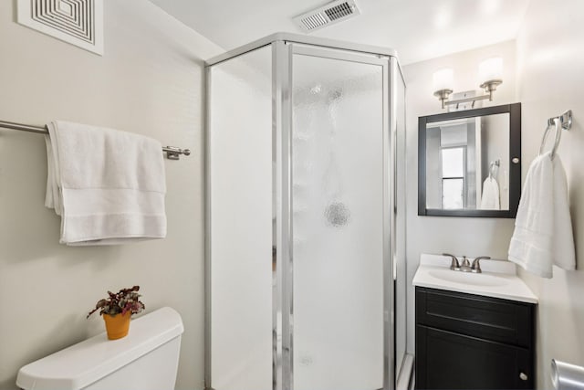 bathroom with toilet, a stall shower, vanity, and visible vents