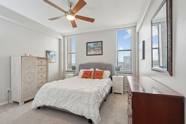 bedroom with light carpet, a textured ceiling, and multiple windows