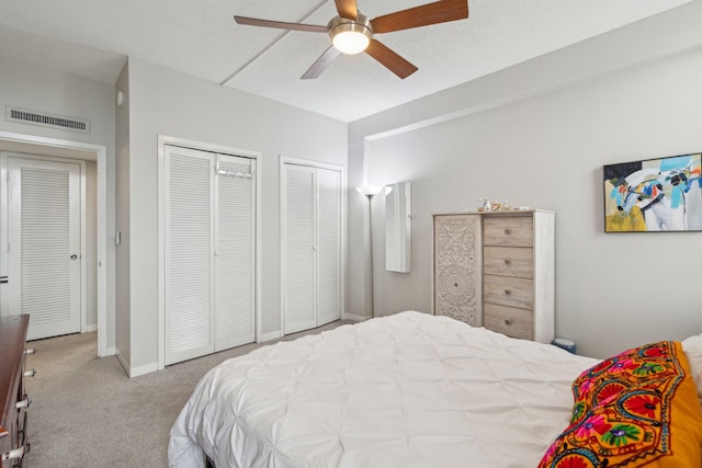 bedroom featuring baseboards, visible vents, a ceiling fan, carpet floors, and multiple closets