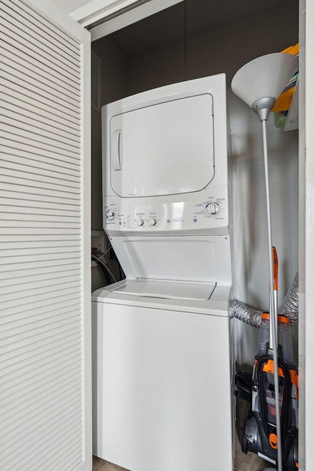 clothes washing area with laundry area, visible vents, and stacked washer and clothes dryer