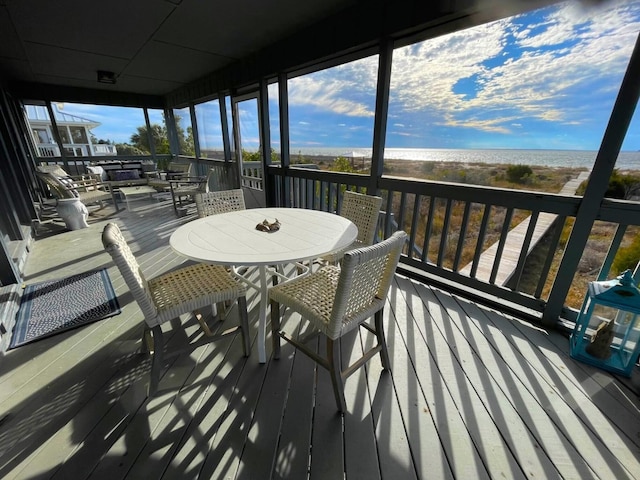 wooden terrace featuring a water view and a view of the beach