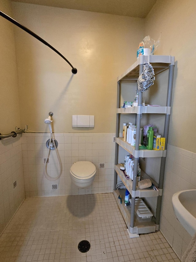 bathroom with tile patterned flooring, toilet, and tile walls