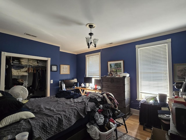 bedroom featuring a chandelier, a closet, ornamental molding, and hardwood / wood-style flooring