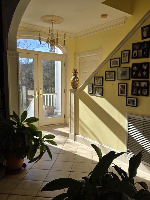 entryway featuring french doors, light tile patterned flooring, a notable chandelier, and ornamental molding