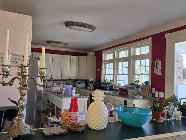 kitchen with a wealth of natural light, crown molding, and white cabinets