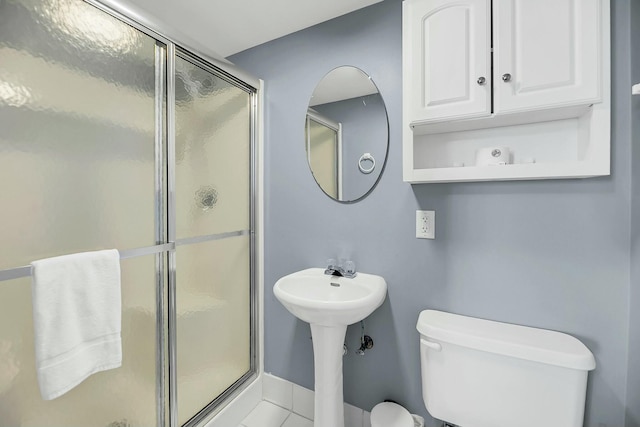 bathroom with tile patterned flooring, toilet, and a shower with shower door