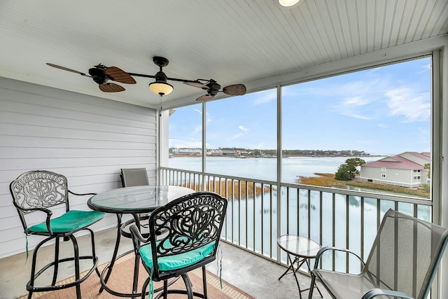 sunroom featuring ceiling fan and a water view