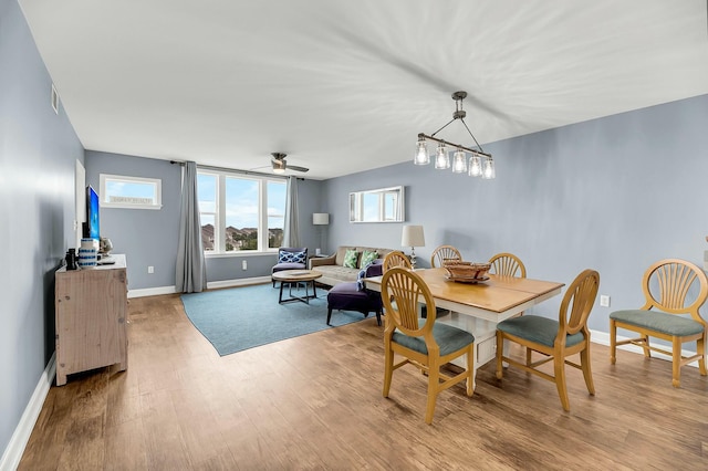 dining room featuring ceiling fan with notable chandelier and light hardwood / wood-style flooring