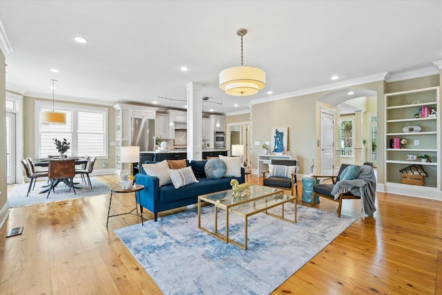 living area featuring ornamental molding, light wood-type flooring, arched walkways, recessed lighting, and baseboards