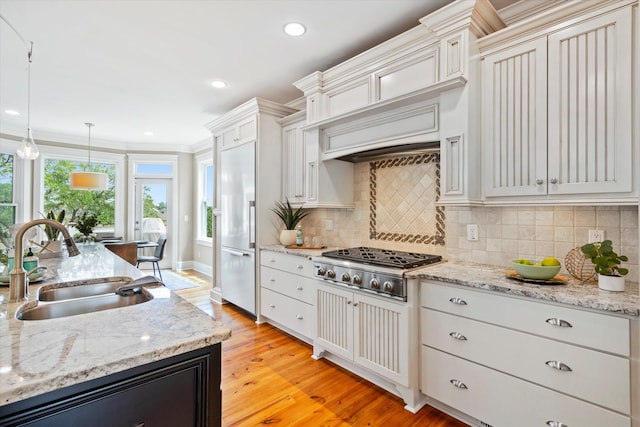 kitchen featuring a sink, stainless steel gas cooktop, built in refrigerator, backsplash, and light wood finished floors