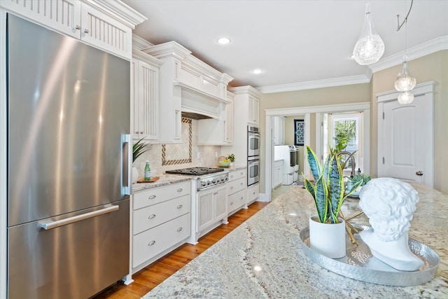 kitchen with appliances with stainless steel finishes, ornamental molding, decorative backsplash, white cabinetry, and light wood-type flooring