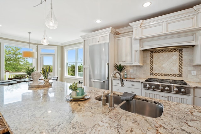 kitchen featuring stainless steel appliances, a sink, healthy amount of natural light, tasteful backsplash, and crown molding