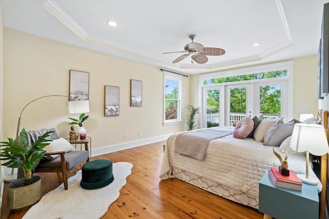 bedroom featuring a raised ceiling, wood-type flooring, baseboards, recessed lighting, and crown molding