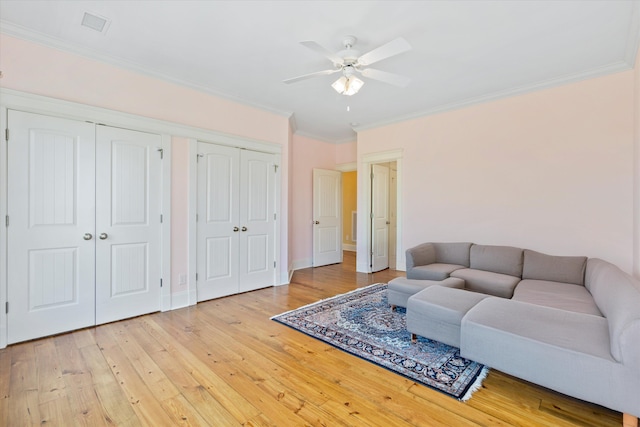 living area with a ceiling fan, ornamental molding, light wood-style flooring, and baseboards