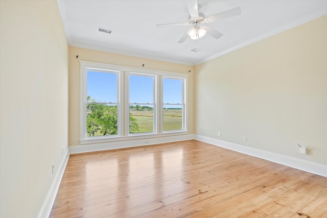 empty room with ornamental molding, light wood-type flooring, and baseboards