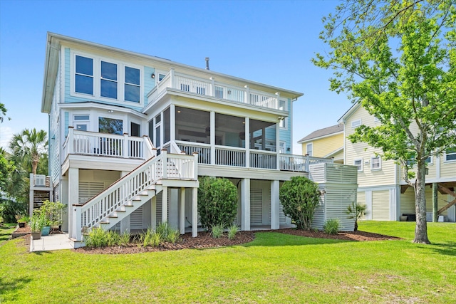 rear view of house featuring stairway, a sunroom, and a yard