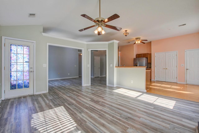 unfurnished living room with lofted ceiling, crown molding, ceiling fan, and wood-type flooring