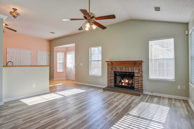 unfurnished living room featuring light wood-type flooring, a brick fireplace, and ceiling fan