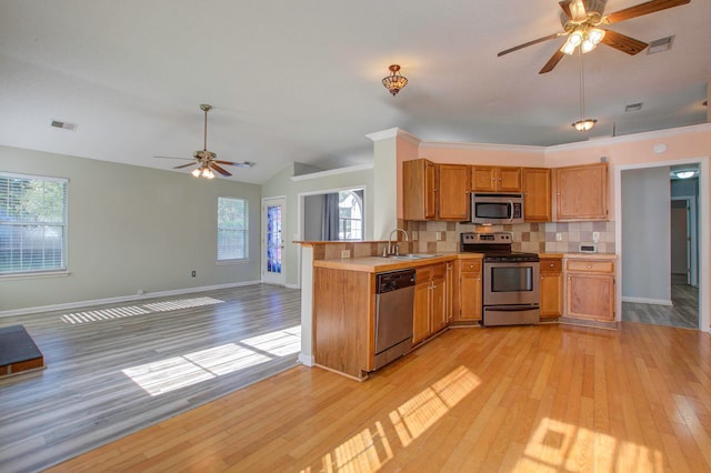 kitchen with light hardwood / wood-style flooring, stainless steel appliances, sink, kitchen peninsula, and ceiling fan