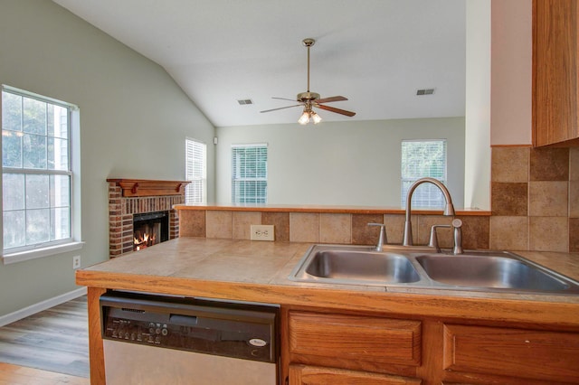 kitchen with a healthy amount of sunlight, a brick fireplace, and stainless steel dishwasher