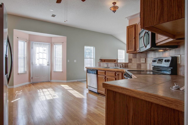 kitchen with a textured ceiling, light hardwood / wood-style flooring, appliances with stainless steel finishes, sink, and ceiling fan