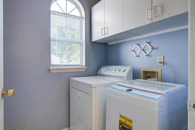 clothes washing area featuring cabinets and washer and dryer